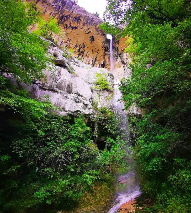 Tall Copot (Sopot) Waterfall dropping through a hole in the rock.