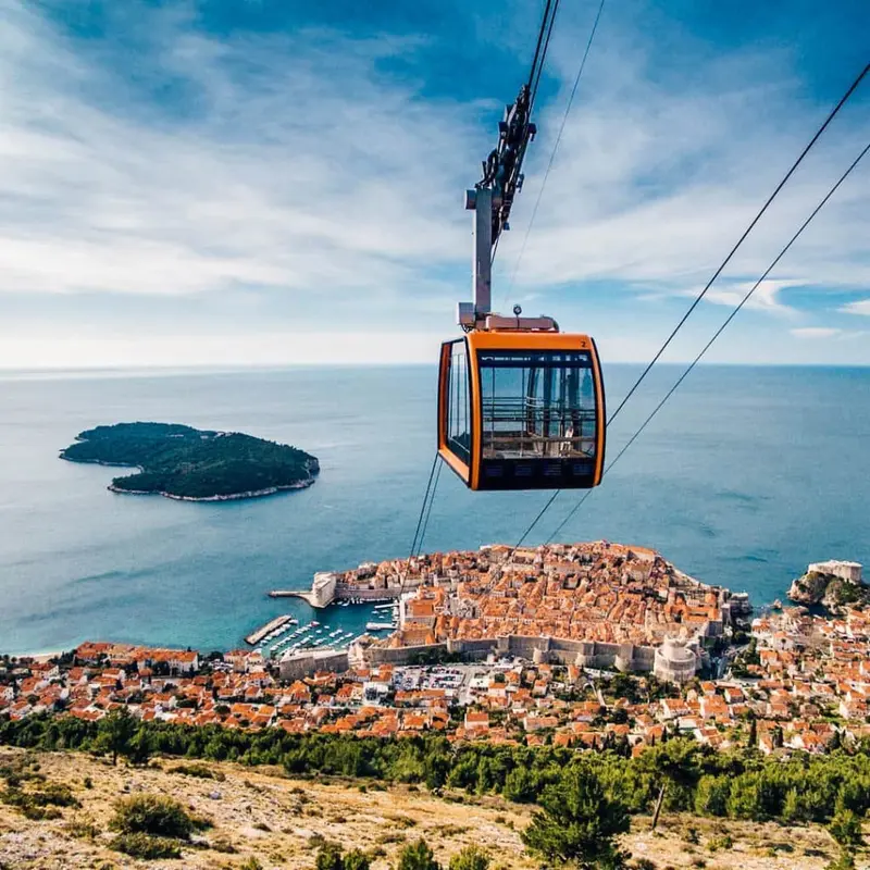 Inside a Dubrovnik cable car cabin looking out over the coastline.