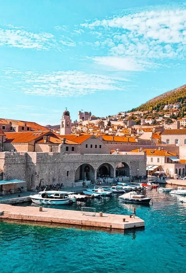 People walking the docks in Dubrovnik's Old Port with boats moored.