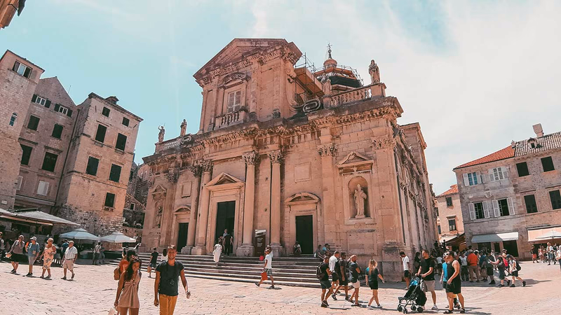 Dubrovnik Cathedral exterior in summer, with visitors walking through Old Town Dubrovnik.