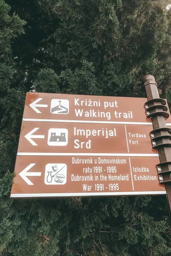Mount Srđ hiking trailhead with signpost and stone steps.