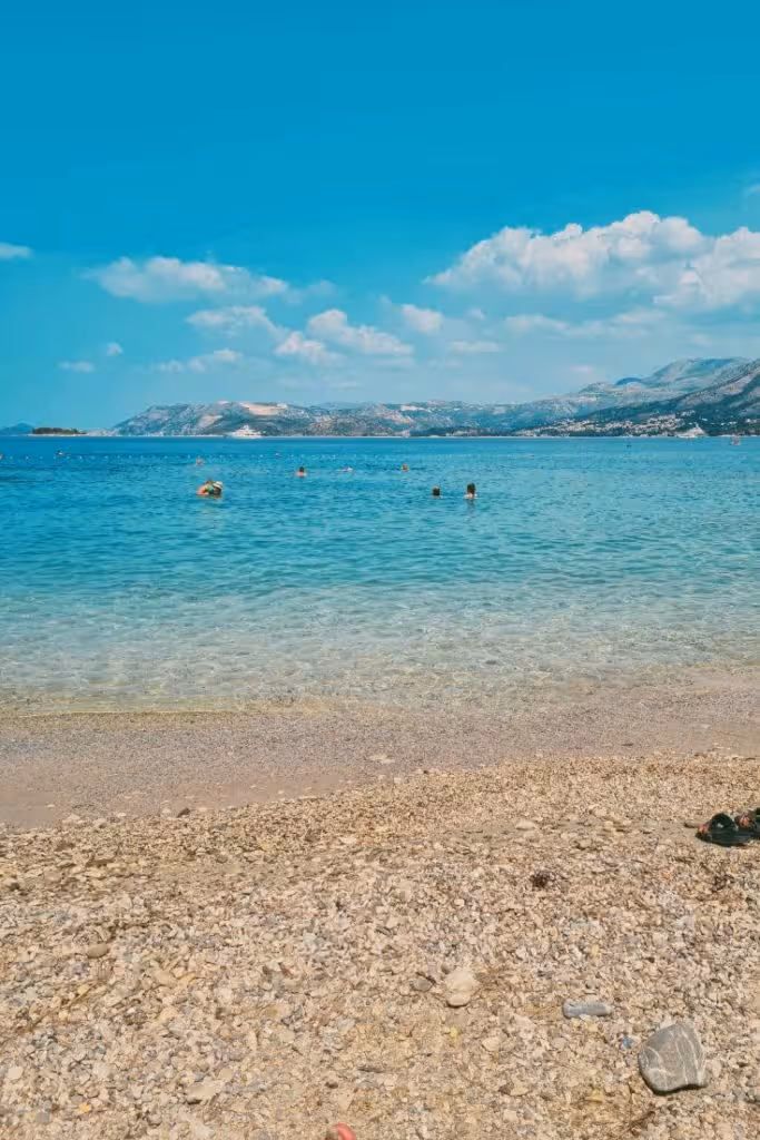 Žal Beach Cavtat with umbrellas and swimmers