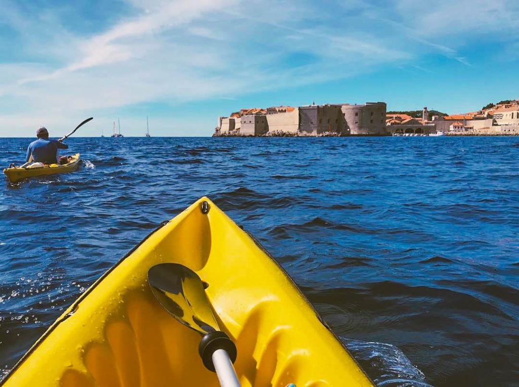 Kayaker paddling toward Dubrovnik Old Town and Porporela lighthouse.