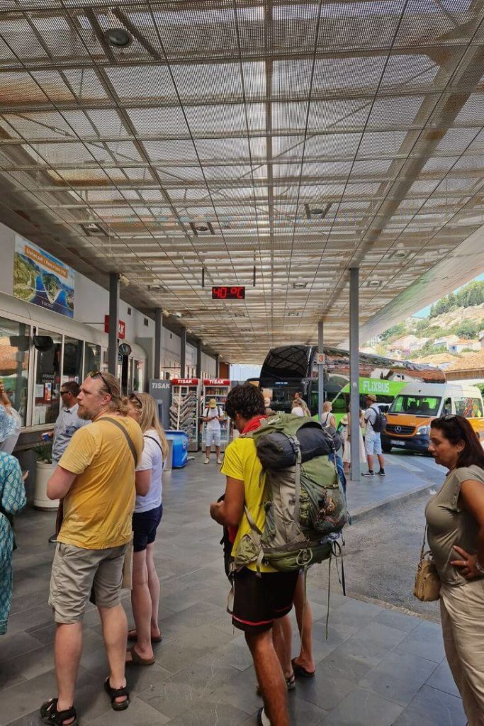Interior view of Dubrovnik main bus terminal with passengers waiting and buses at the platforms.