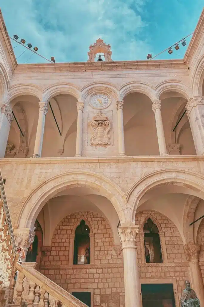 Ground floor view of inner courtyard of Rectors Palace with statue of Miho Pracat with sky in the background