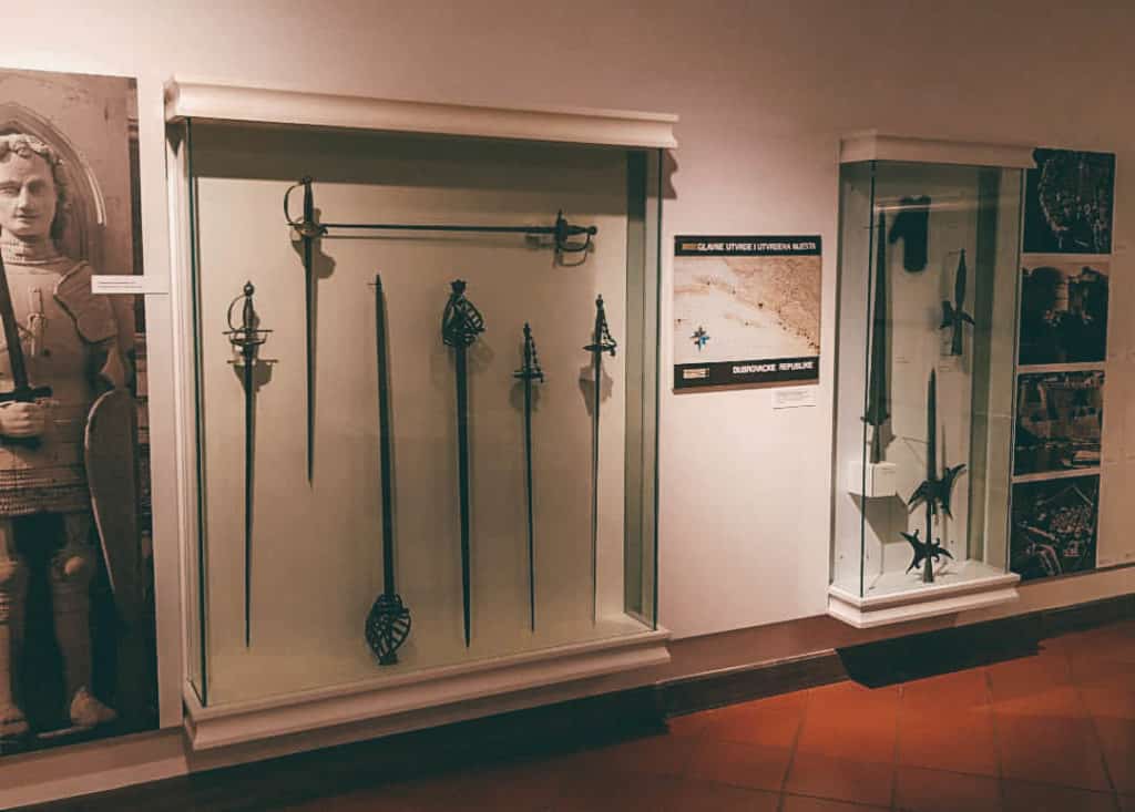 Photo of glass encased displays of old arms, weapons and firearms used in the defense of Dubrovnik
