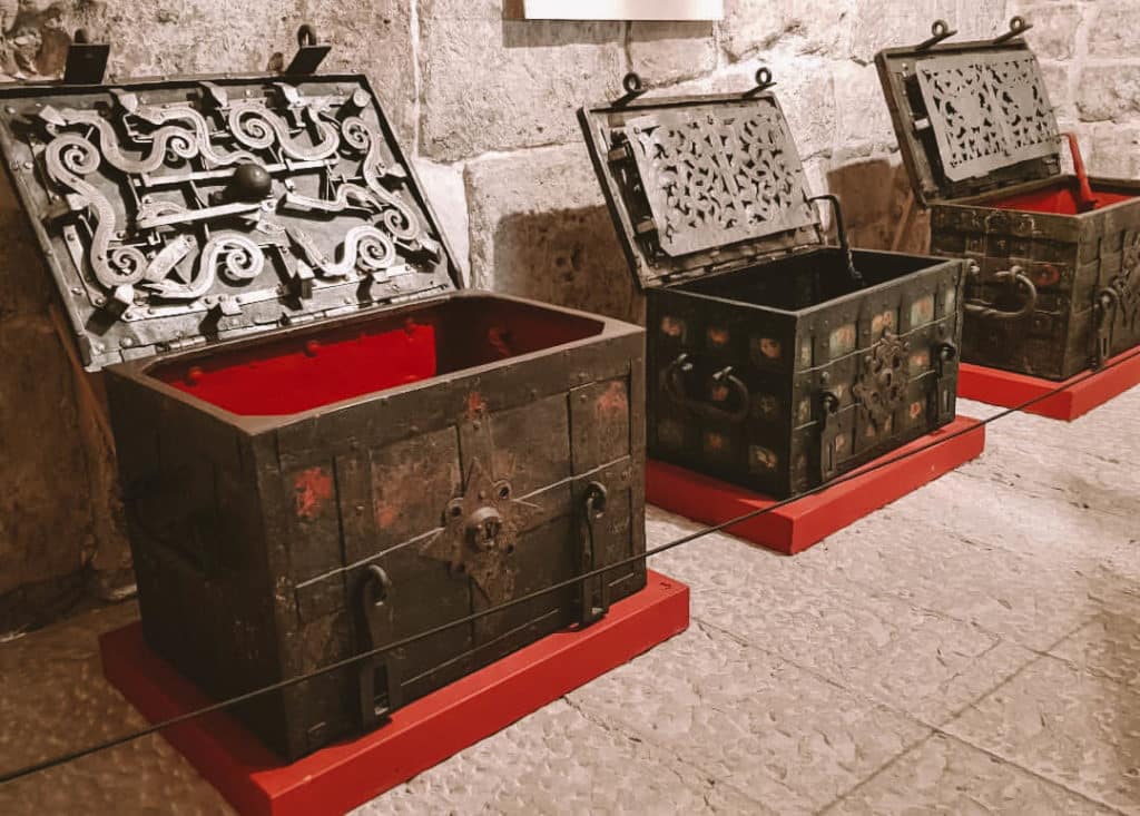 Photo of Palace dungeon that shows displays of various historical items. In the image are intricate mechanisms of chests used by Dubrovnik citizens to hold treasure and valuables.