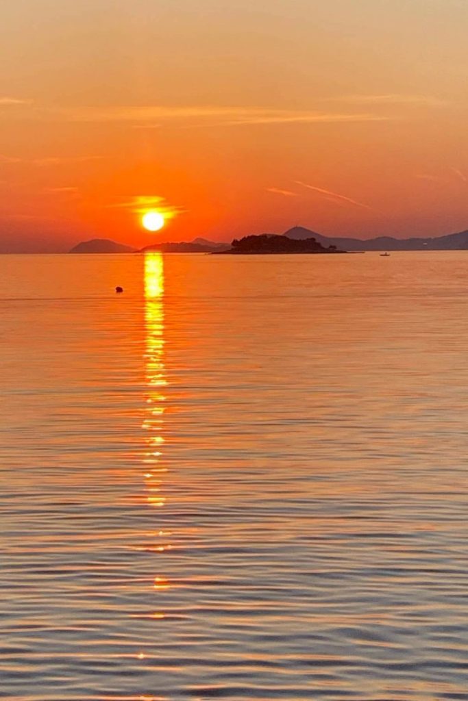 View from the boat going from Cavtat at the sunset going down in the distance over Dubrovnik